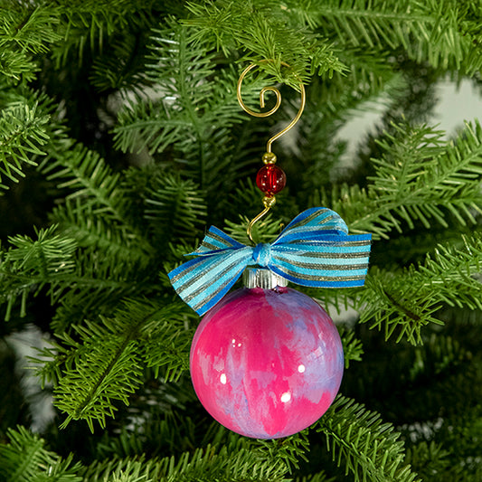 The Kelly Hand Painted Glass Ball Ornament is a mix of pink, blue, purple, white, silver shimmer and a blue striped shimmer ribbon. Painted using fluid acrylic and acrylic paints.