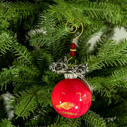The Rose Hand Painted Glass Ball Ornament is red with a hint of pink, metallic gold, silver shimmer and a black and white shimmer ribbon. Painted using fluid acrylic and acrylic paints. Displayed on a Christmas tree.