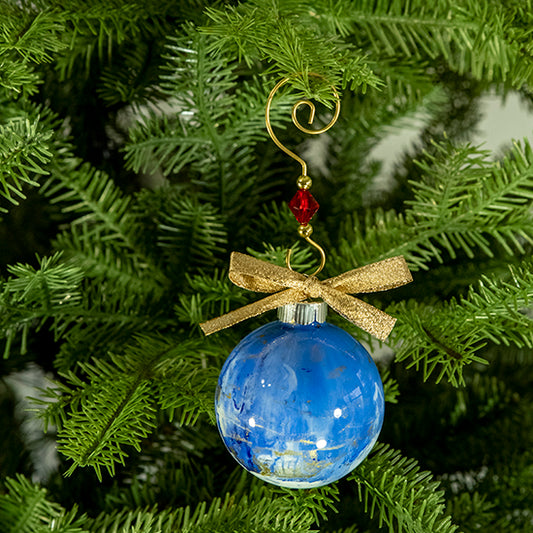 The Trish Hand Painted Glass Ball Ornament is blue and white with a hint of metallic gold and a gold shimmer ribbon. Painted using fluid acrylic and acrylic paints. Displayed on a Christmas tree.