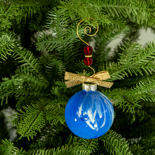 The Jenny Hand Painted Glass Ball Ornament is blue and white with a hint of metallic silver and a gold shimmer ribbon. Painted using fluid acrylic and acrylic paints. Displayed on a Christmas tree.